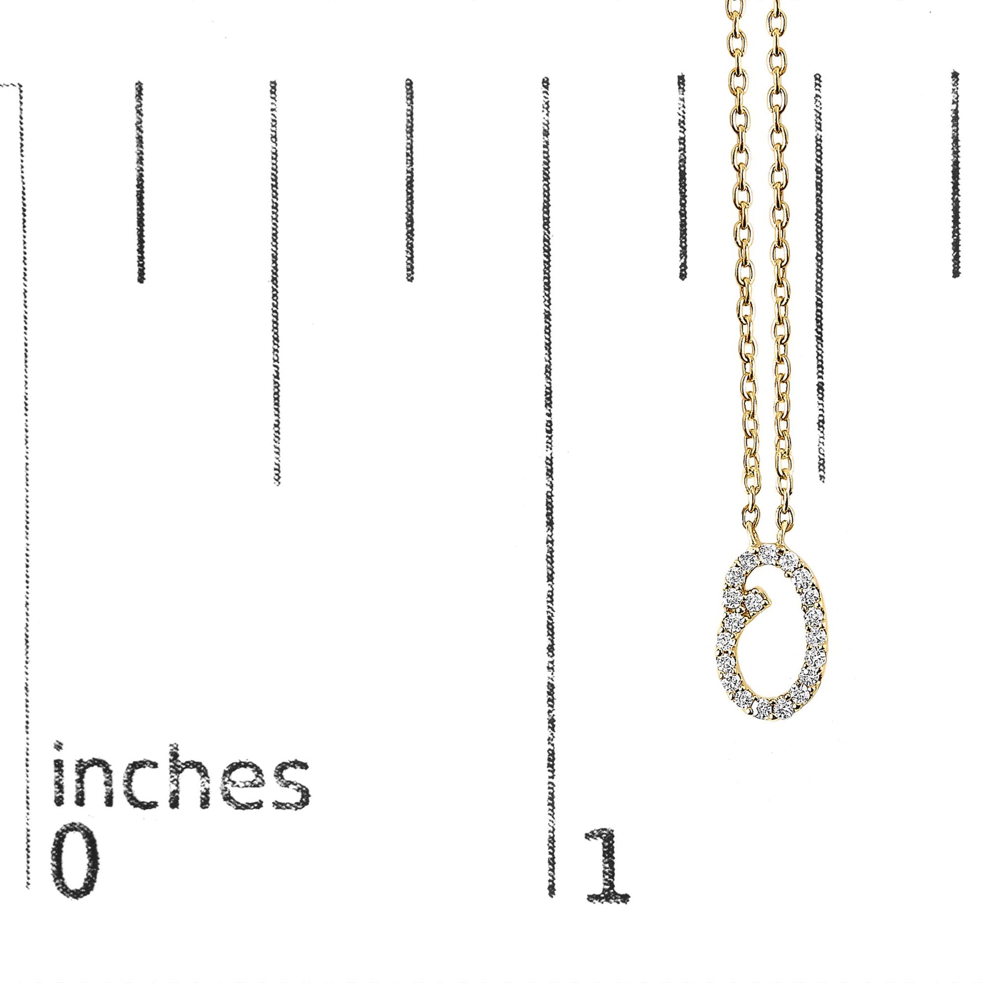 Yellow metal necklace with an oval-shaped pendant set with round white gemstones in a micro-pave setting, shown close-up on a scale with inch markings.