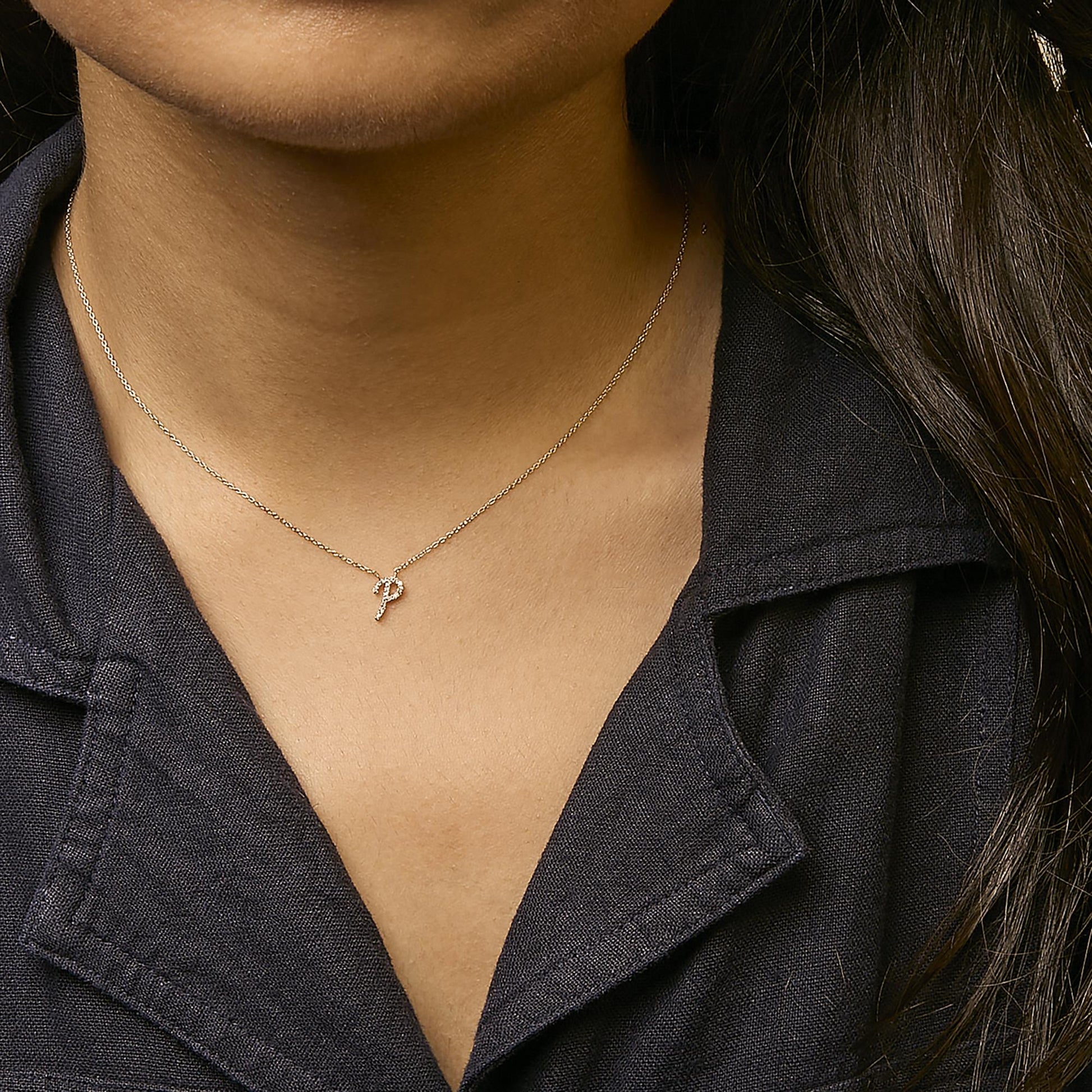 Yellow metal necklace with a small pendant featuring round white gemstones in a micro-pave setting, shown worn on a model from a front angle.