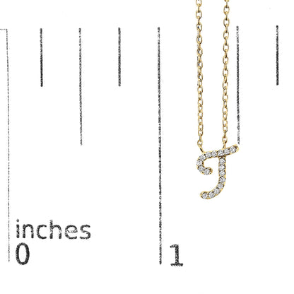 Yellow metal necklace with a pendant in the shape of the letter 'J' adorned with round white gemstones in a micro-pave setting, shown hanging on a scale with inch measurements, front view.
