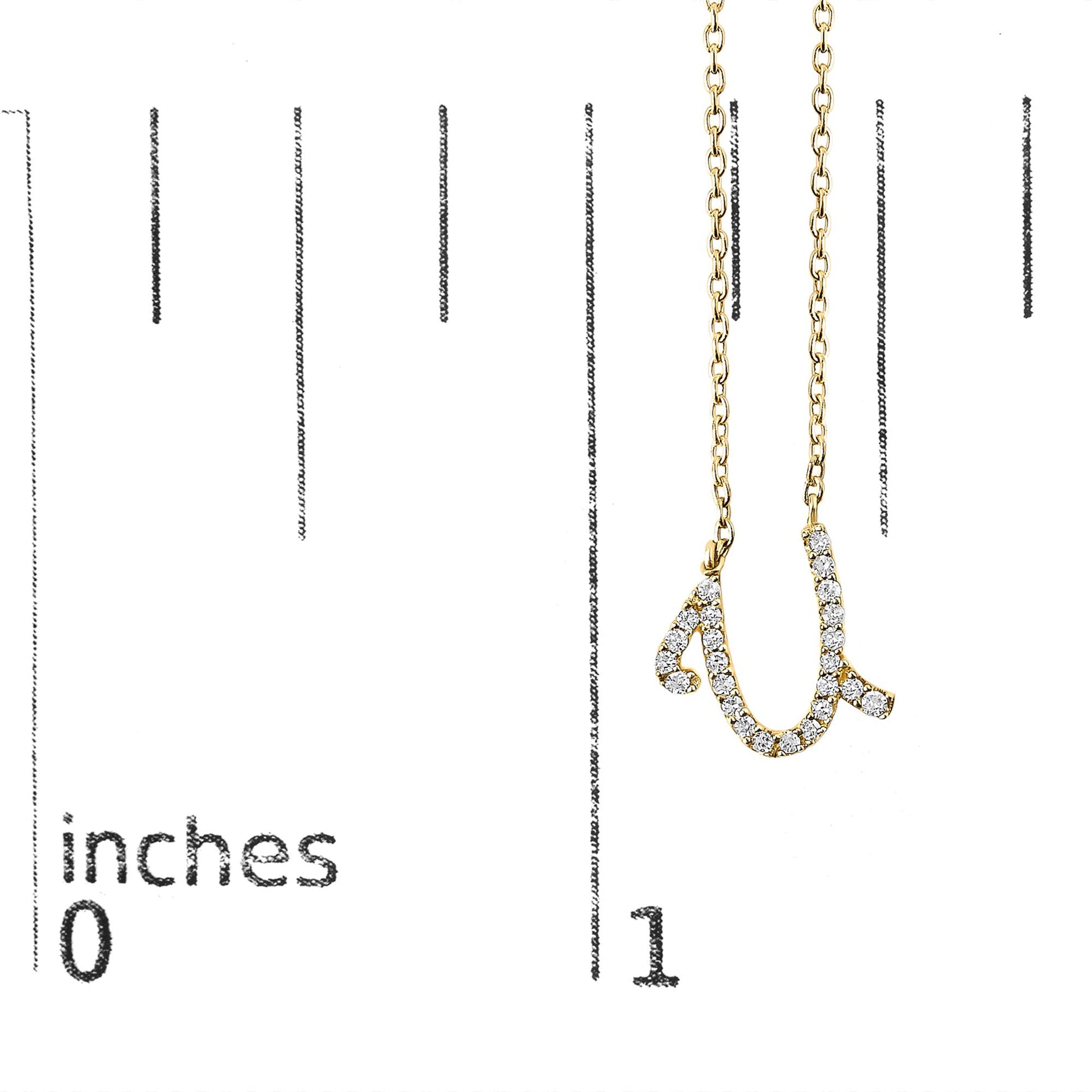 Close-up front angle of a yellow metal necklace pendant shaped like a cursive lowercase letter 'u,' decorated with round white gemstones in a micro-pave setting, shown on a scale marked in inches.