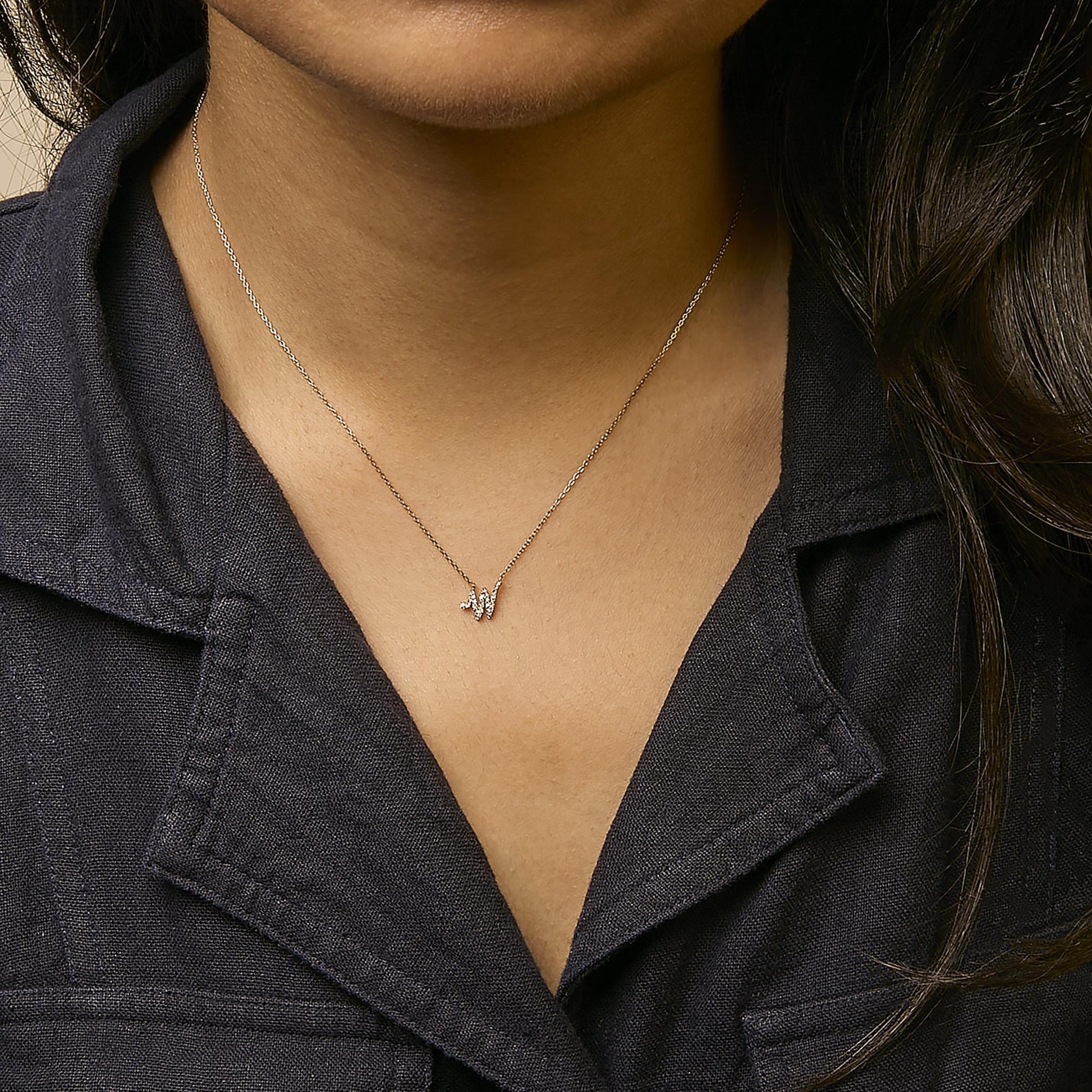 Yellow necklace with a small pendant featuring multiple white gemstones in a cluster, shown worn on a model from a front angle.