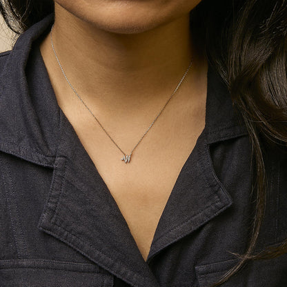 Yellow necklace with a small pendant featuring multiple white gemstones in a cluster, shown worn on a model from a front angle.