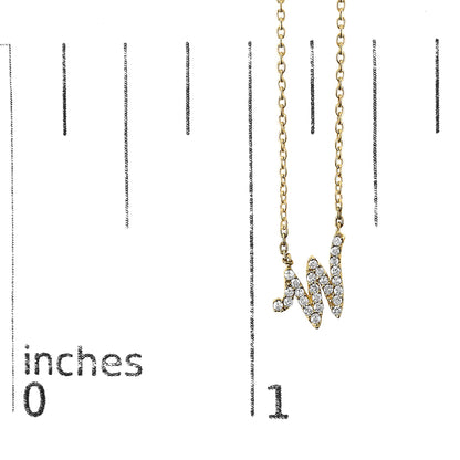 Close-up front view of a yellow metal necklace with a pendant in the shape of the letter 'W' set with white round gemstones, shown hanging on a scale marked in inches.