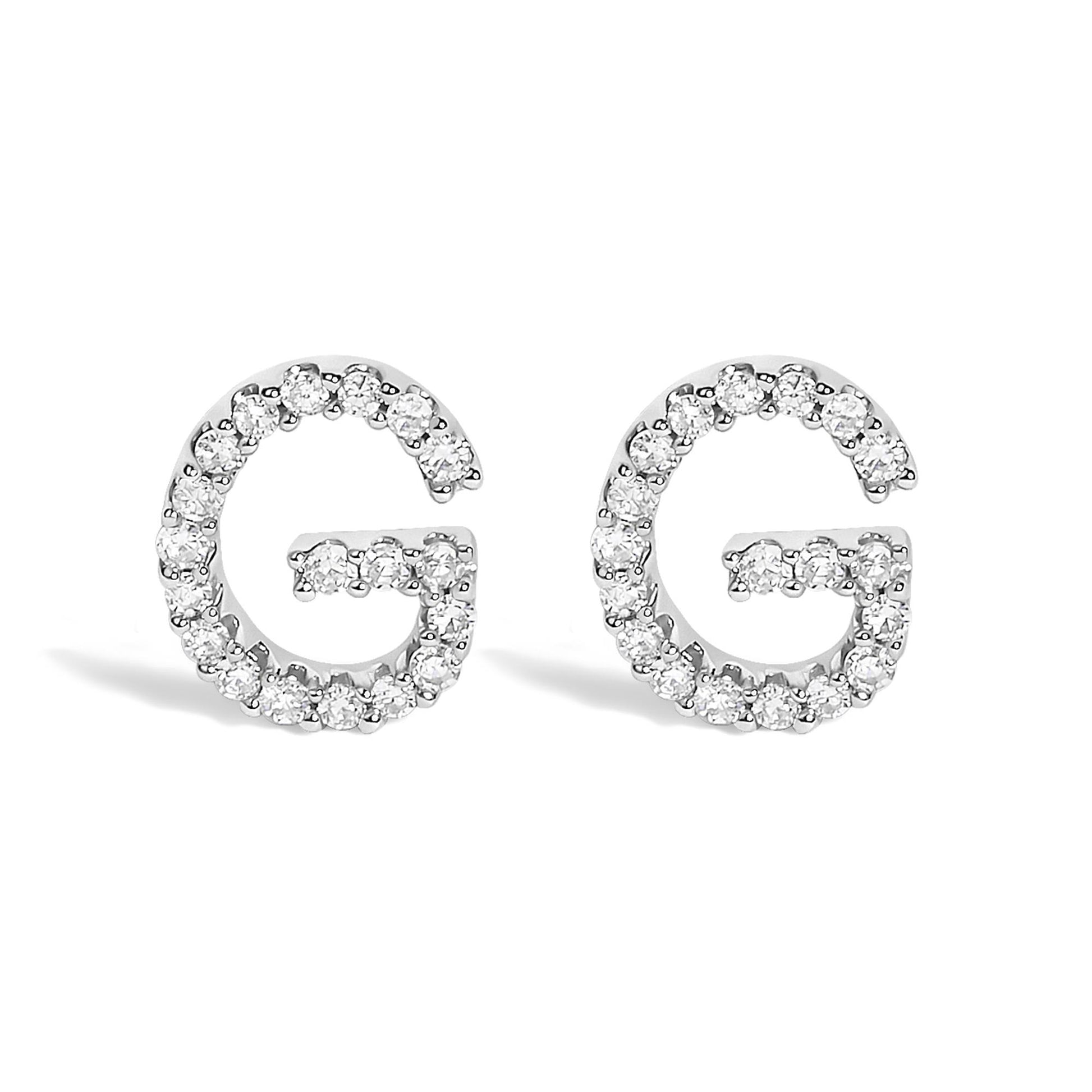 Front view of a pair of white metal earrings shaped like the letter G, each outlined with round white gemstones in a micro-pave setting.