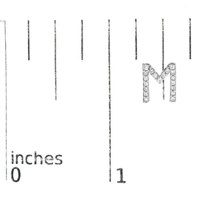 White metal earring shaped like the letter M, featuring round white gemstones in a micro-pave setting, shown on a scale with inch markings from 0 to 1, front view.