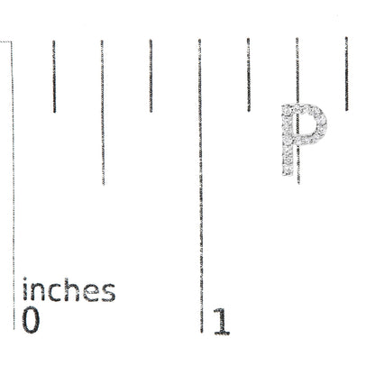 Close-up front angle of a white metal earring shaped like the letter P, set with round white gemstones, shown on a scale marked in inches.