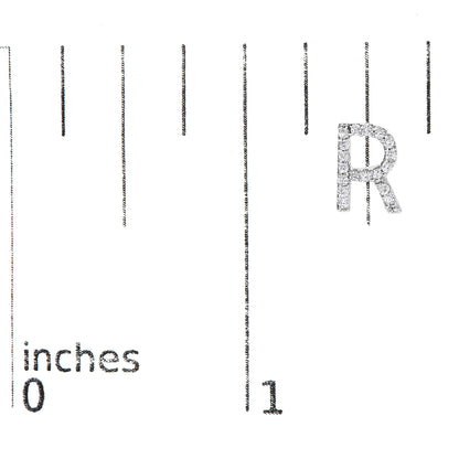 Close-up front angle of a white letter 'R' earring adorned with round white gemstones in a micro-pave setting, shown on a scale with inch markings.