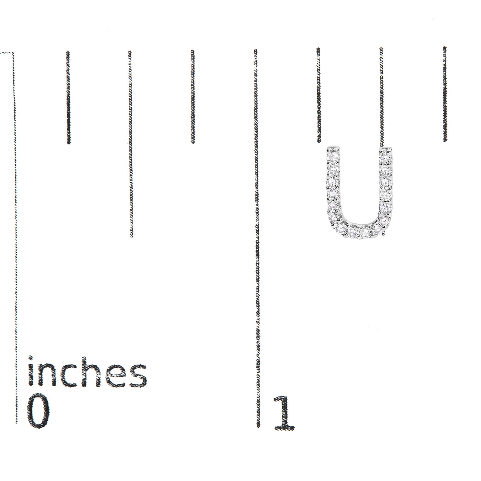 Close-up of a single white metal earring in a U-shape, adorned with round white gemstones in micro-pave setting, shown on a measurement scale.