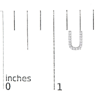 Close-up of a single white metal earring in a U-shape, adorned with round white gemstones in micro-pave setting, shown on a measurement scale.