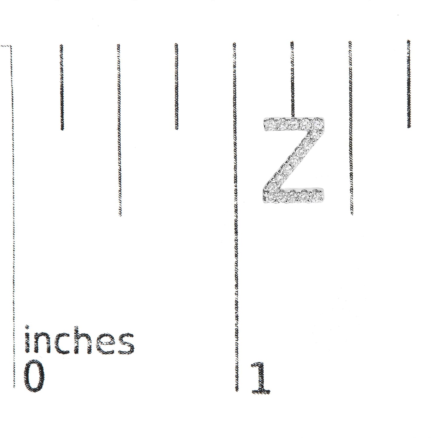 Close-up front view of a single white metal earring shaped like the letter Z, encrusted with round white gemstones in a micro-pave setting, shown on a scale with inch markings.