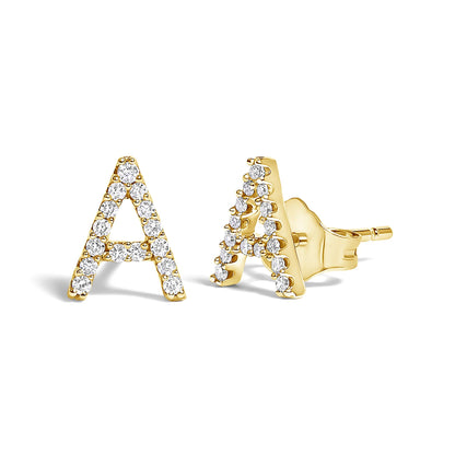 Pair of yellow metal stud earrings shaped like the letter A, adorned with round white gemstones in a micro-pave setting, shown from a front and side angle on a white background.