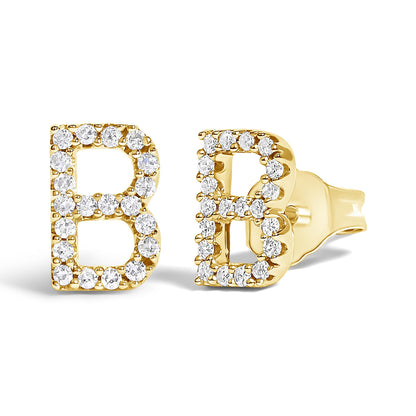 Close-up angled view of a pair of yellow metal earrings shaped as the letter B, each outlined with round white gemstones in a micro-pave setting.