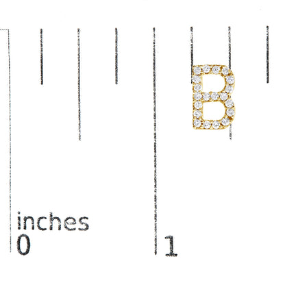 Yellow metal earring in the shape of the letter B, adorned with round white gemstones in a micro-pave setting, shown on a scale from above.