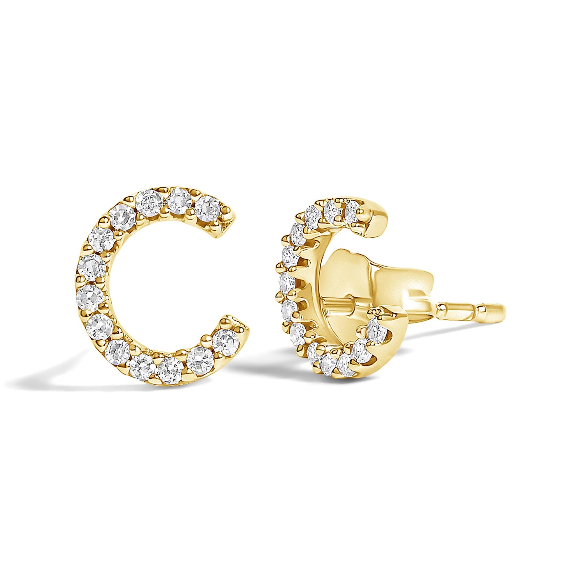 Close-up front and side angled view of yellow metal crescent-shaped stud earrings adorned with round white gemstones in a micro-pave setting.
