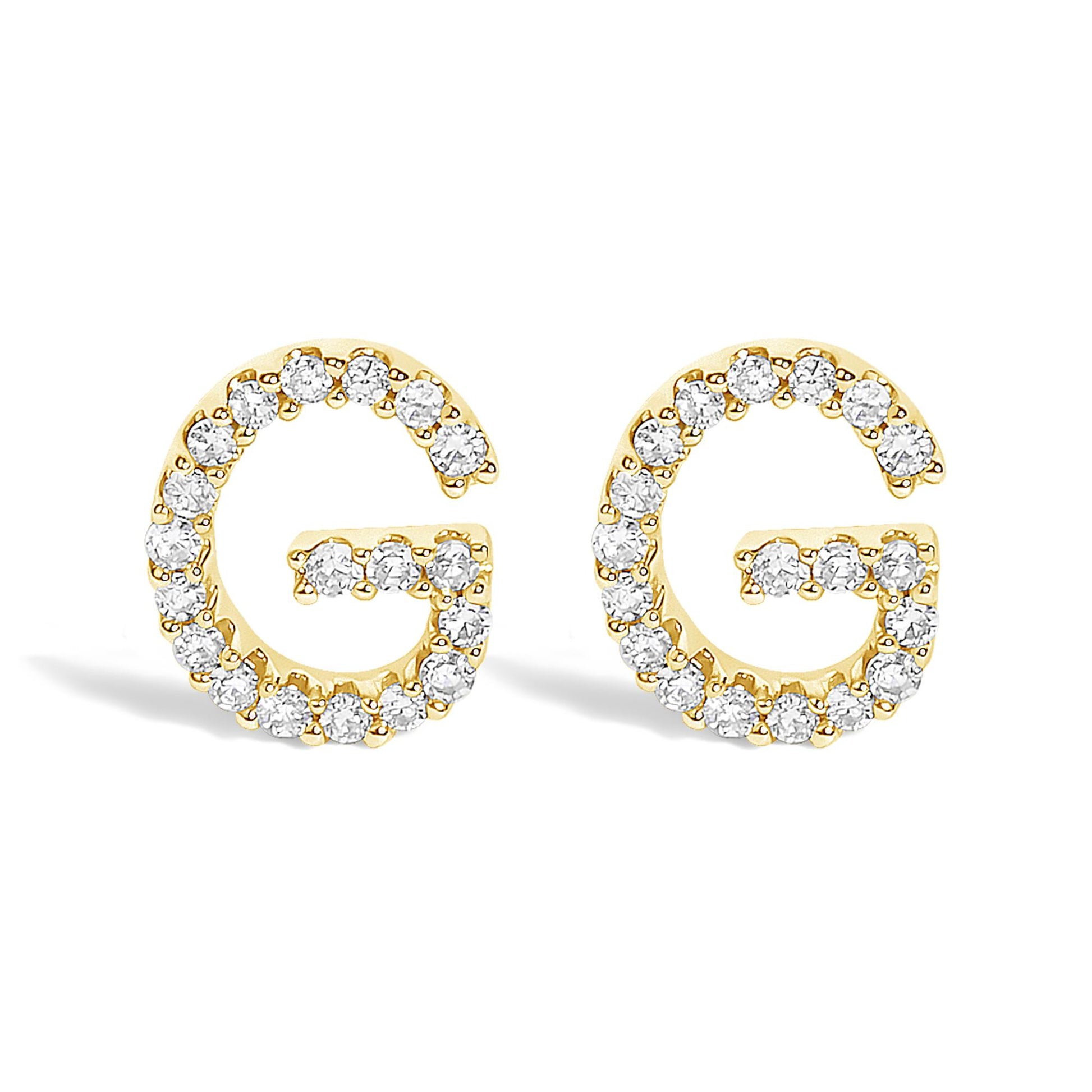 Pair of yellow metal earrings shaped like the letter G, each outlined with round white gemstones in a micro-pave setting, shown from the front angle on a white background.