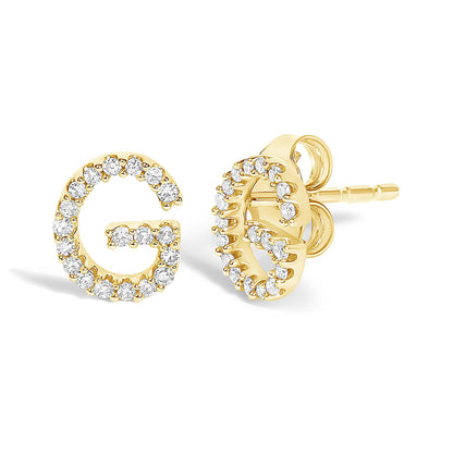 Pair of yellow metal stud earrings shaped like the letter G, each decorated with small round white gemstones in a micro-pave setting, shown in a close-up angled view.