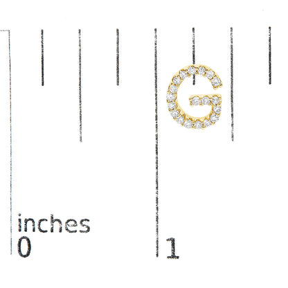 Close-up front view of a yellow metal earring shaped like the letter G and adorned with white round gemstones in a micro-pave setting, shown on a scale.