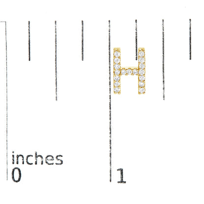 Close-up image of a yellow metal earring in the shape of the letter 'H' with round white gemstones in micro-pave setting, shown on a scale with inches markings, shot from the front.