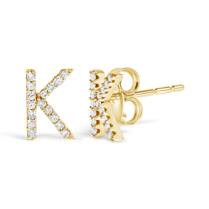 Close-up front and side view of yellow metal stud earrings shaped like the letter 'K' with round white gemstones in a micro-pave setting.
