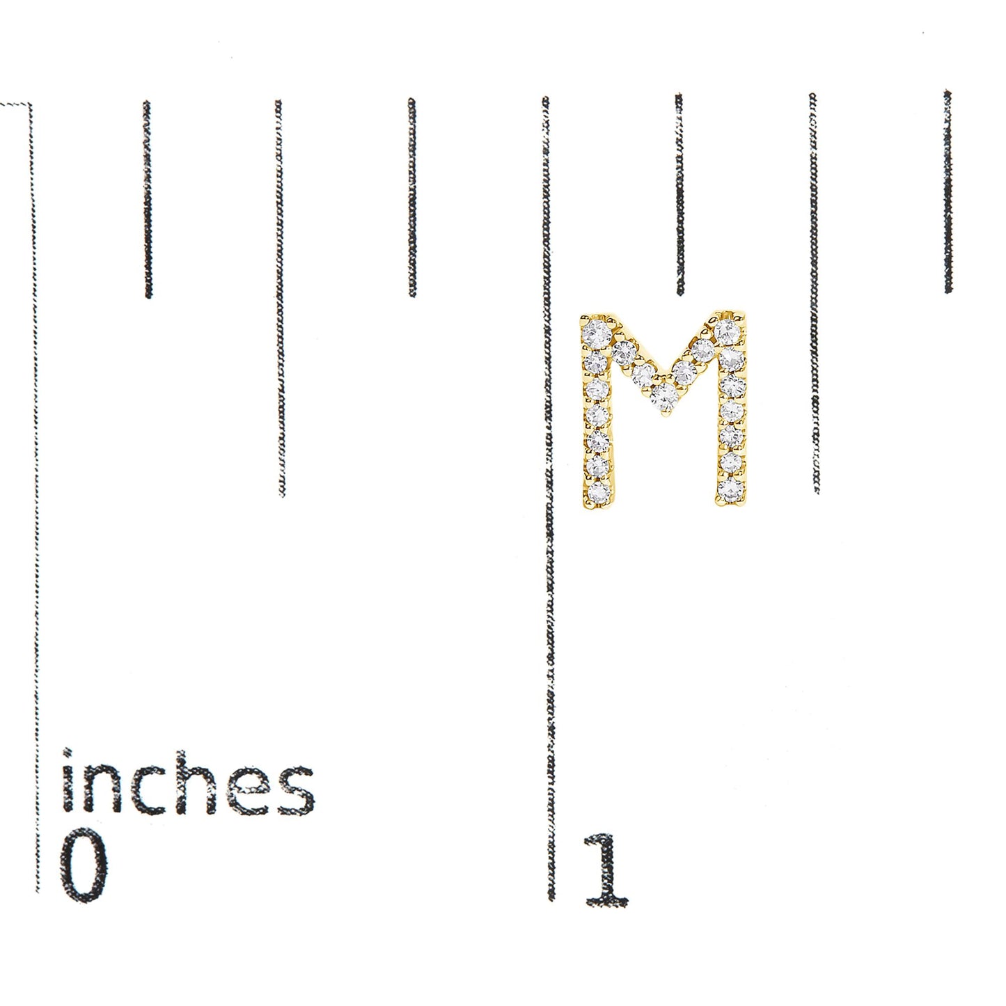 Close-up of a yellow metal earring shaped like the letter M, adorned with small round white gemstones in a micro-pave setting, shown on a scale with inch measurements.