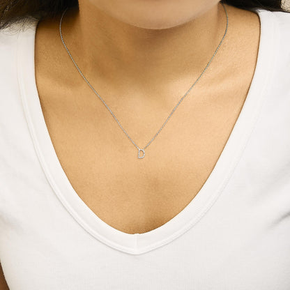 Close-up front angle of a necklace with a white metal chain and a pendant letter 'D' adorned with white gemstones in a micro-pave setting, shown worn on a model.