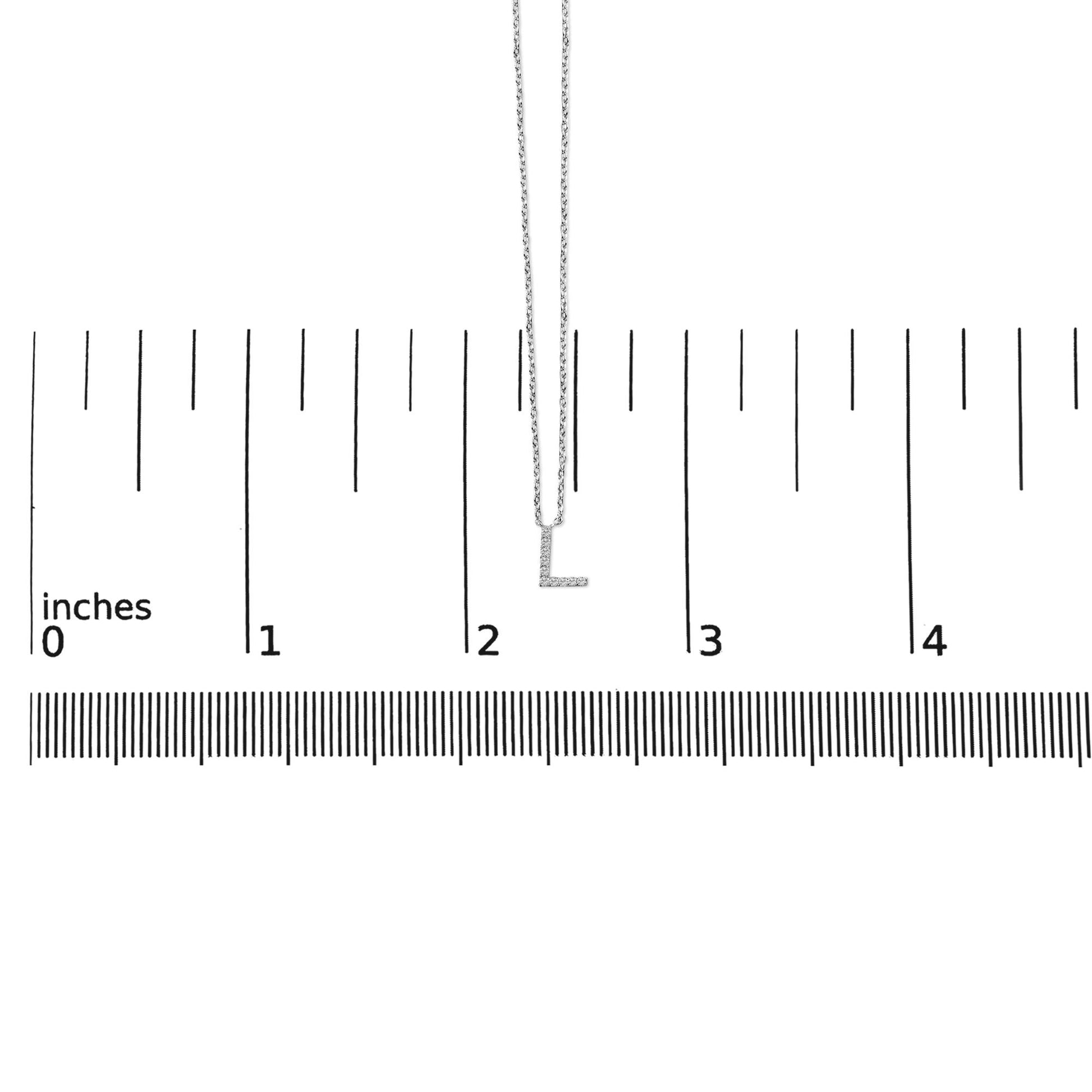 White necklace with a pendant shaped like the letter 'L' encrusted with small white gemstones, shown on a ruler for scale from a front angle.