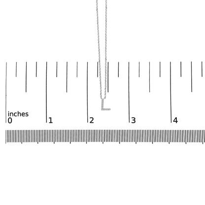 White necklace with a pendant shaped like the letter 'L' encrusted with small white gemstones, shown on a ruler for scale from a front angle.
