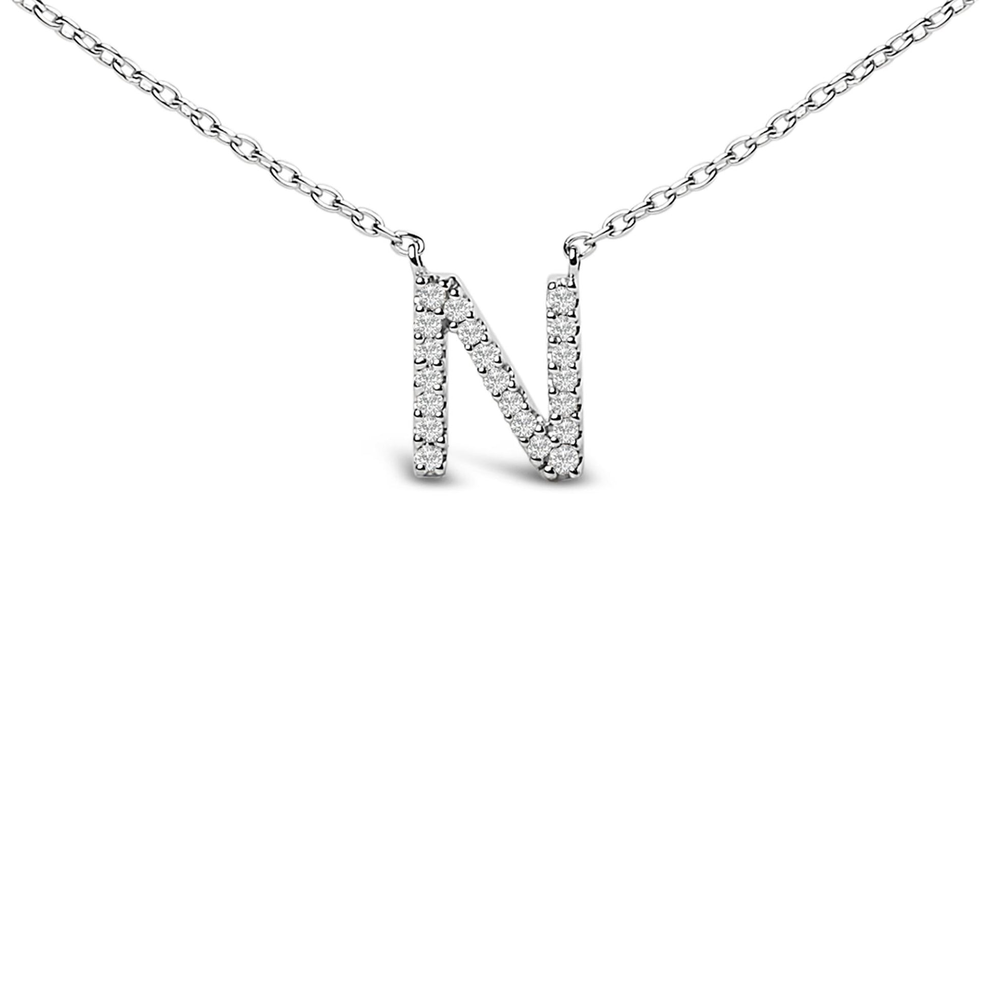 Close-up front view of a white metal necklace with a pendant in the shape of the letter 'N' adorned with small round white gemstones in a micro-pave setting.
