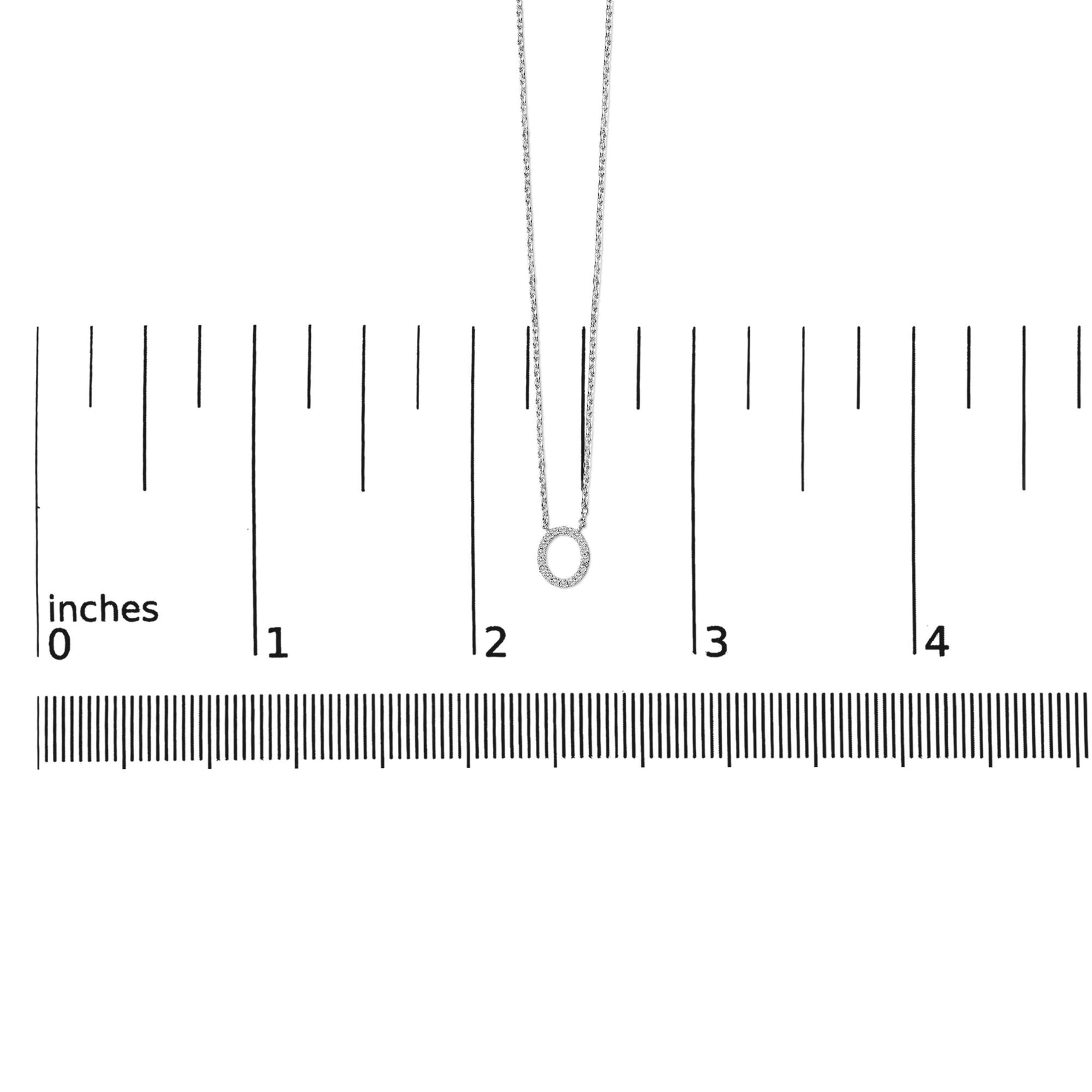 Pendant necklace with oval-shaped pendant featuring round white gemstones in micro-pave setting, shown flat on a ruler scale from front angle.