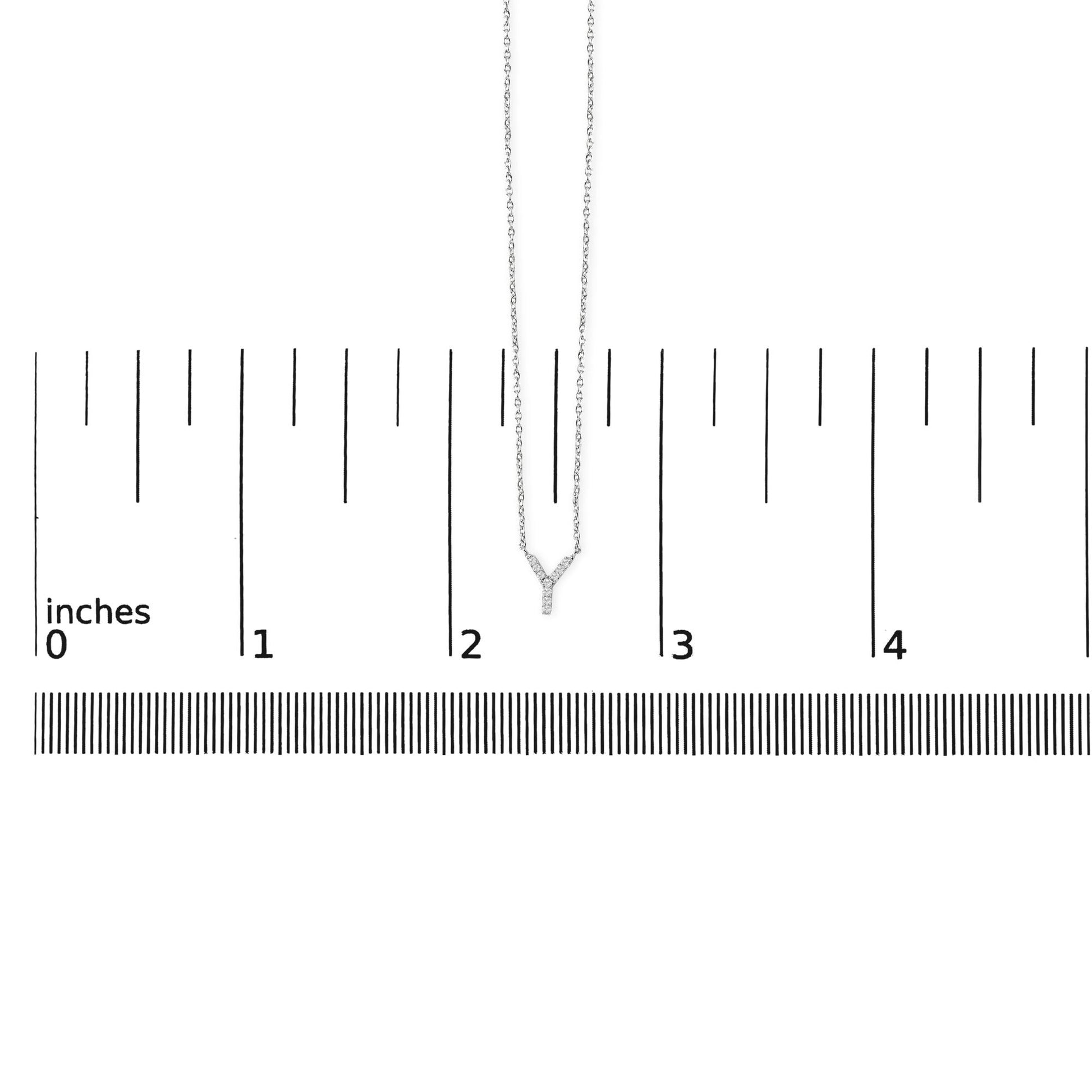 White metal necklace with Y-shaped pendant featuring small round white gemstones in micro-pave setting, shown hanging on a ruler scale from a front angle.