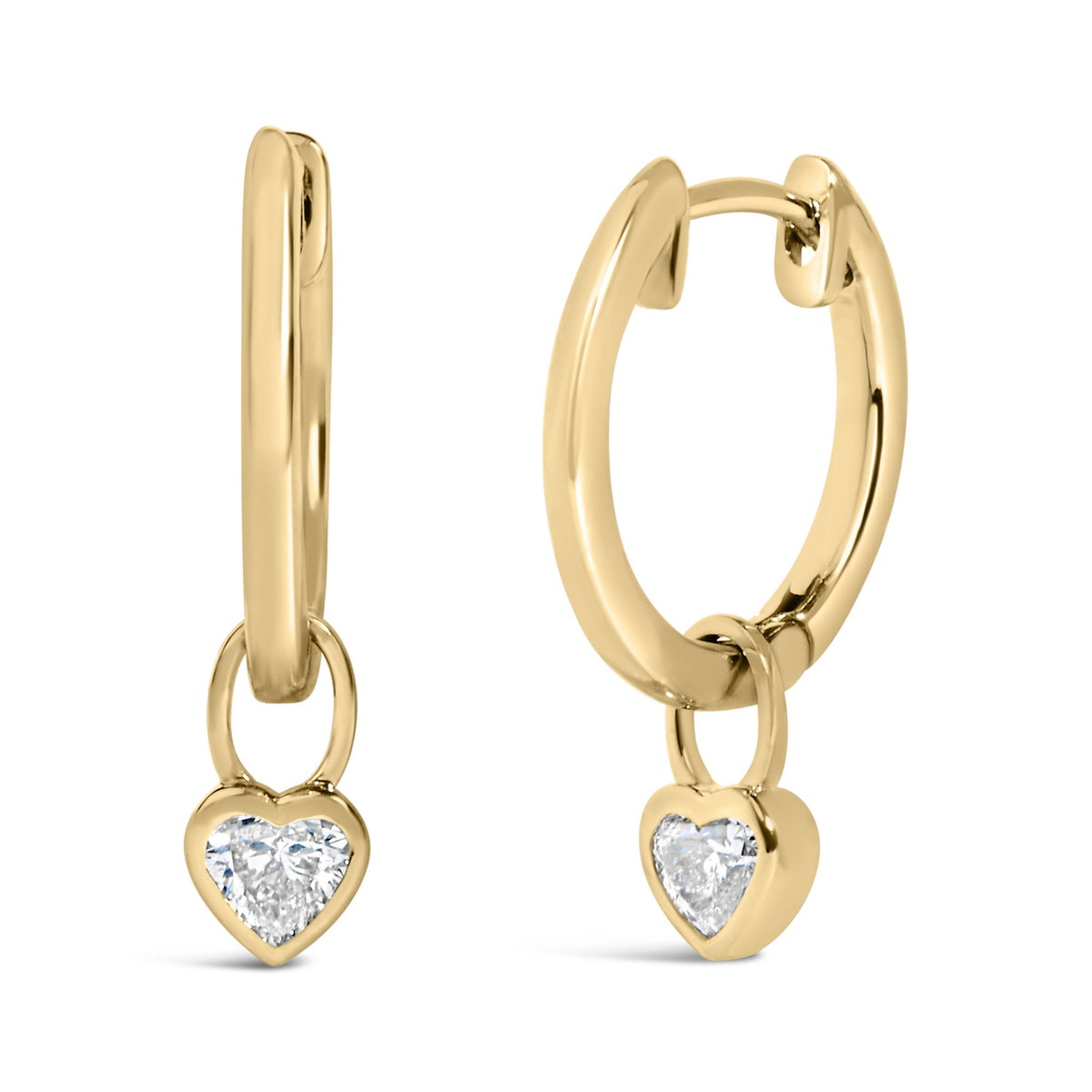 Close-up front angle view of yellow metal hoop earrings with dangling heart-shaped charm set with white gemstones in bezel setting, shown on a white background.