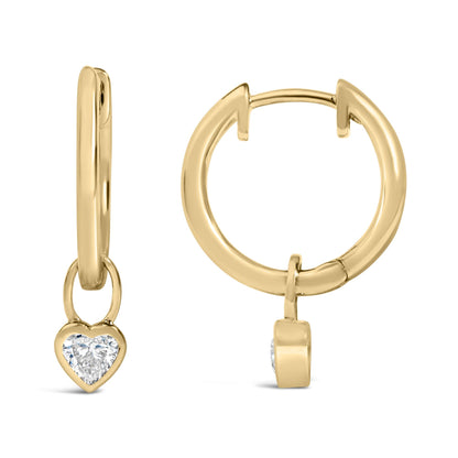 Close-up front and side view of yellow metal hoop earrings with dangling heart-shaped white gemstones in bezel settings, shown on a white background.