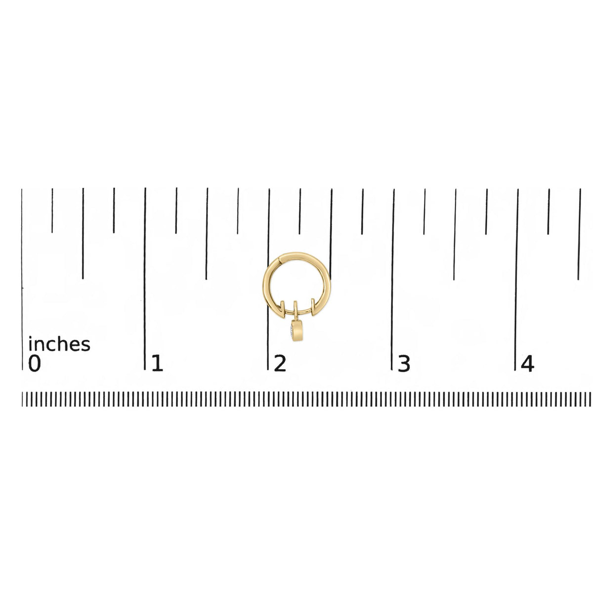 Close-up front view of a single yellow metal hoop earring with a small dangling piece featuring a white heart-shaped gemstone in bezel setting, shown on a ruler scale background.