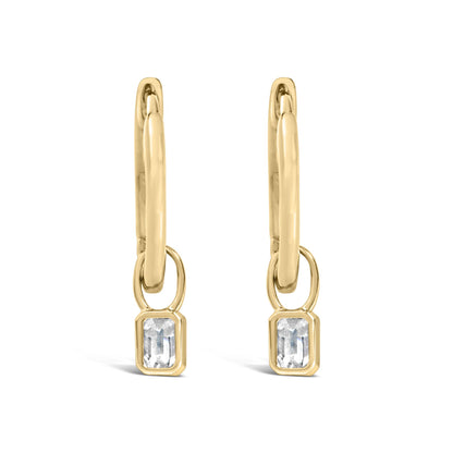 Front angle close-up of yellow metal drop earrings featuring linked oval shapes and bezel-set white emerald-shaped gemstones at the bottom.