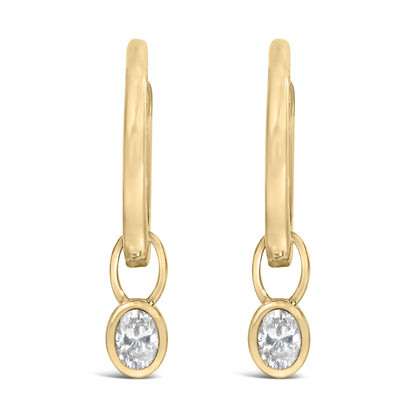 Front view of yellow metal drop earrings with oval-shaped white gemstones in bezel settings.