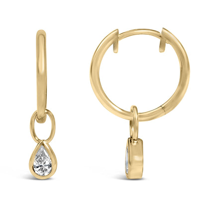 Close-up front and side view of yellow metal hoop earrings with dangling pear-shaped white gemstones in bezel settings.