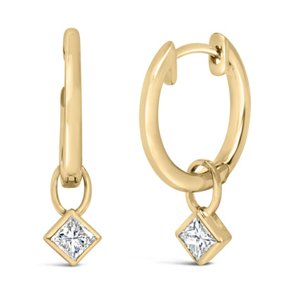 Close-up front and side view of a pair of yellow metal hoop earrings with small hanging princess-shaped white gemstones in bezel settings.