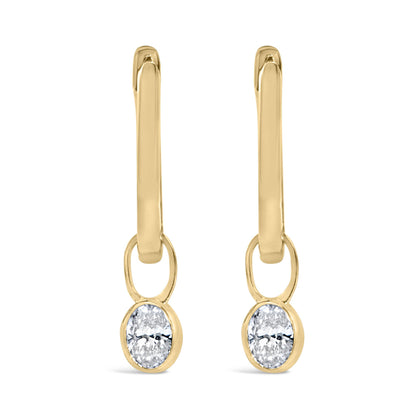 Close-up front view of yellow metal drop earrings with oval-shaped white gemstones in bezel settings at the bottom.
