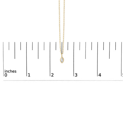 Close-up front view of a yellow necklace with a marquise-shaped white gemstone in a bezel setting, shown on a scale.