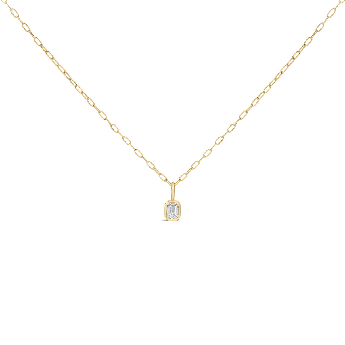 Close-up front view of a yellow necklace with a bezel-set emerald-shaped white gemstone pendant on a chain link.