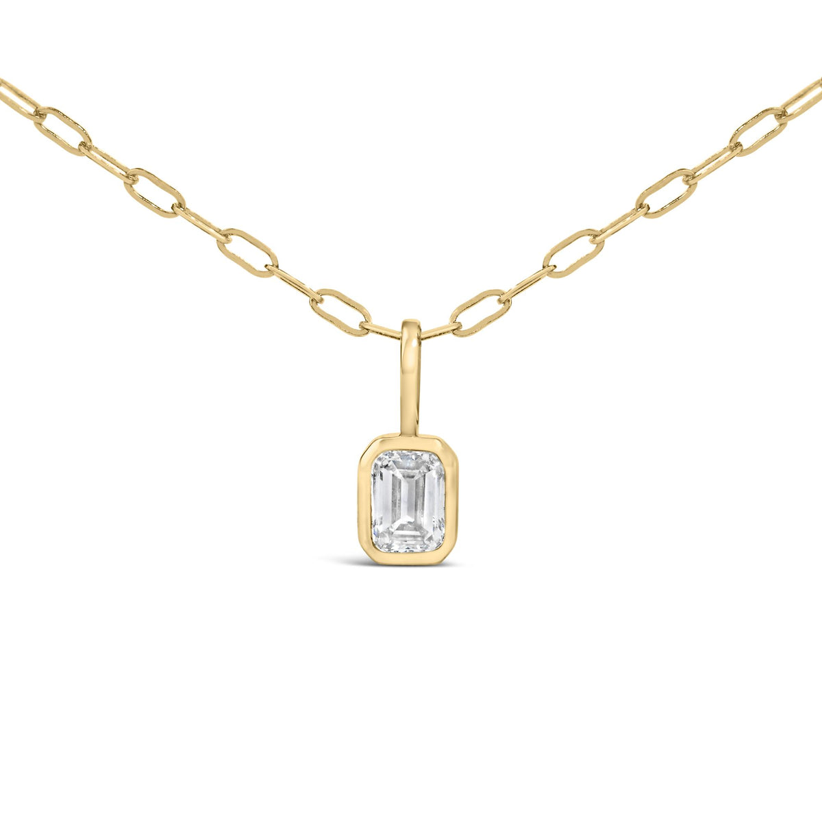 Close-up front angle of a yellow metal necklace with an emerald-shaped white gemstone in a bezel setting pendant.
