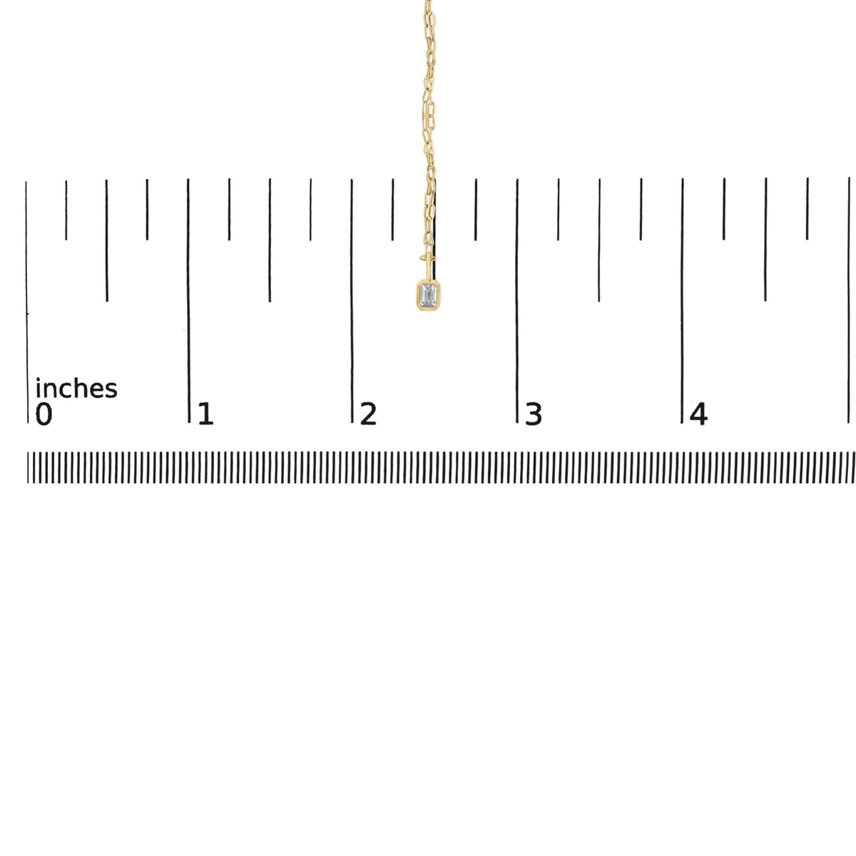 Close-up front view of a yellow metal necklace displayed on a scale, featuring a small emerald-shaped white gemstone in a bezel setting at the pendant's end.