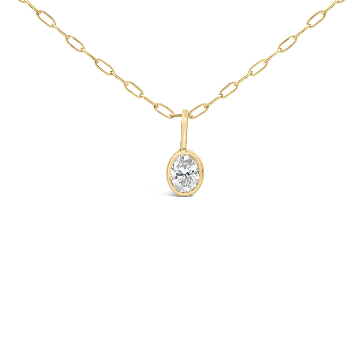 Close-up angled view of a yellow metal necklace with oval-shaped bezel-set white gemstone pendant.