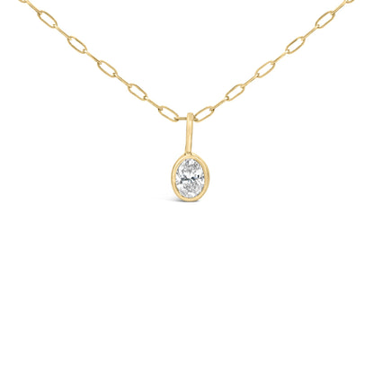 Close-up angled view of a yellow metal necklace with oval-shaped bezel-set white gemstone pendant.