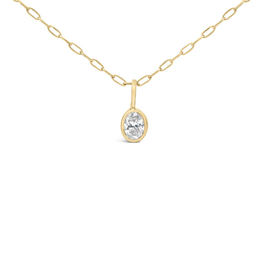 Close-up angled view of a yellow metal necklace with oval-shaped bezel-set white gemstone pendant.