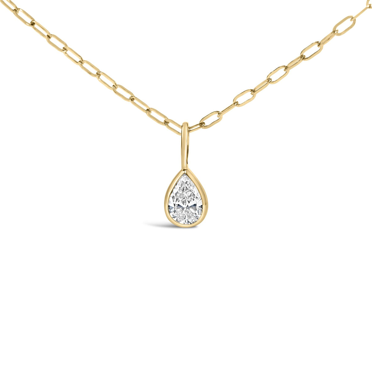 Close-up front view of a yellow metal necklace with a pear-shaped white gemstone in a bezel setting pendant.