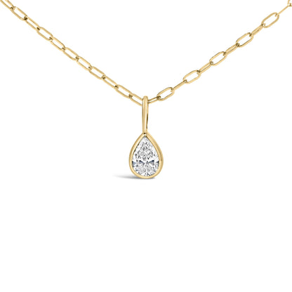 Close-up front view of a yellow metal necklace with a pear-shaped white gemstone in a bezel setting pendant.