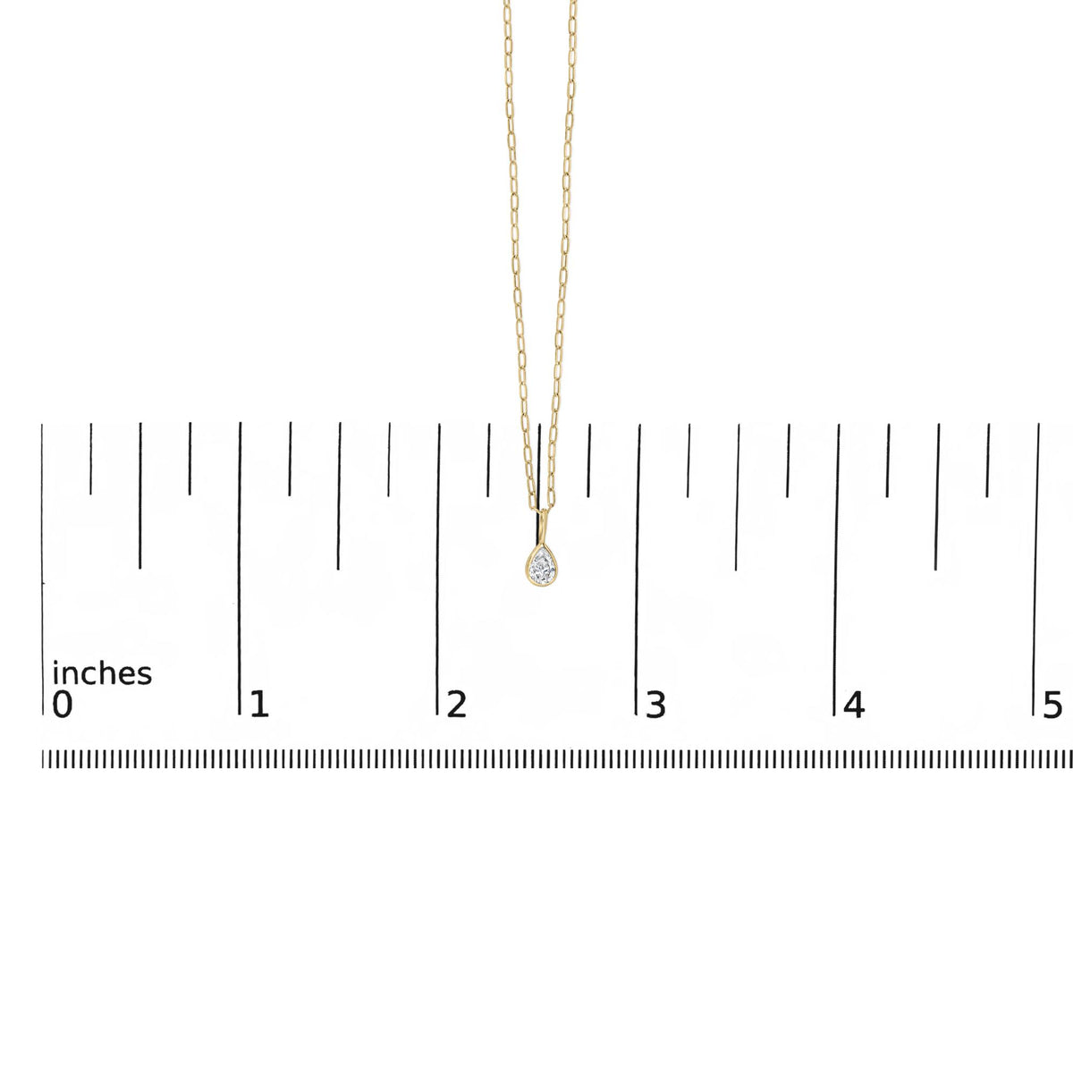 Close-up front view of a yellow metal necklace with a pear-shaped white gemstone in a bezel setting, shown on a ruler scale.