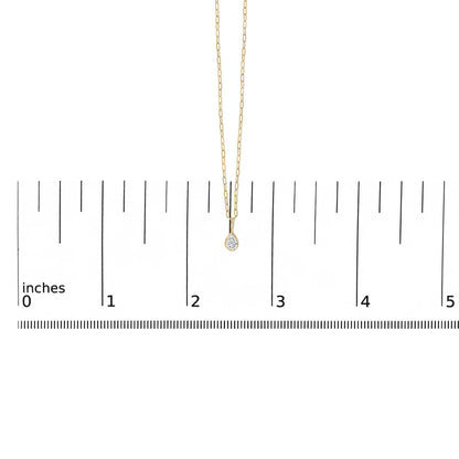 Close-up front view of a yellow metal necklace with a pear-shaped white gemstone in a bezel setting, shown on a ruler scale.