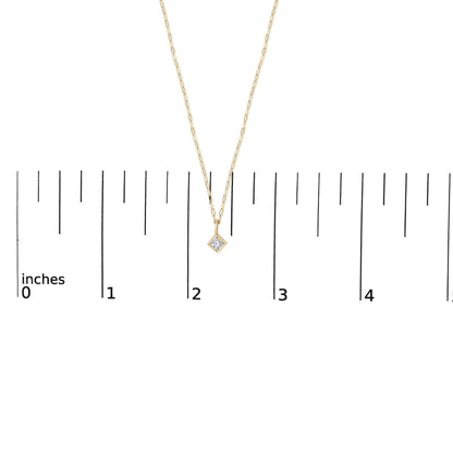 Close-up front view of a yellow metal necklace shown on a scale with a princess shape white gemstone in a bezel setting pendant.